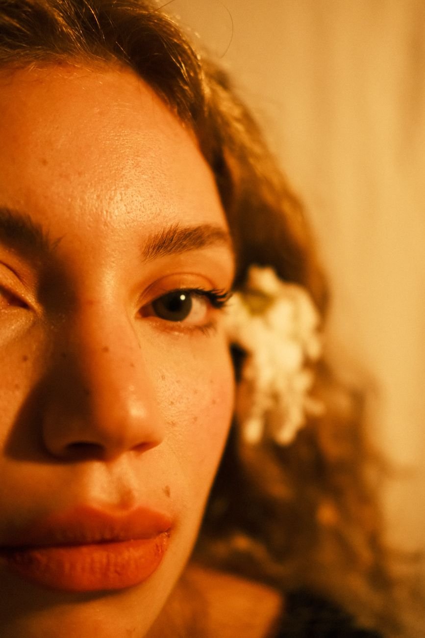 Warm editorial portrait of a woman with freckles and flowers — beauty brand campaign photography